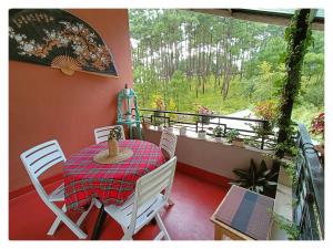 a room with a table and chairs on a balcony at Sha Ri Loum Homestay in Shillong