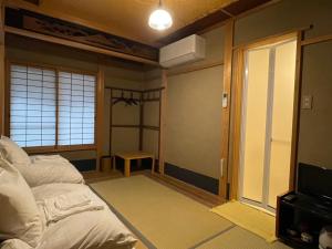 a room with a bed and a window and a tv at Nagomi-Ryokan Yuu in Kyoto