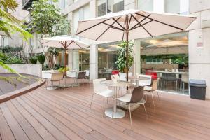 a patio with tables and chairs and an umbrella at Sky Coyoacan Depto con terraza privada in Mexico City