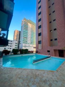 a large swimming pool in a city with tall buildings at Apto frente à praia - Guilhermina in Praia Grande