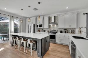 a kitchen with white cabinets and a large island with bar stools at Large 6BR Themed Family Villa Near Disney world in Kissimmee