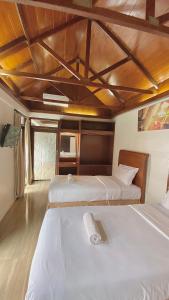 a bedroom with two beds and a wooden ceiling at chrome hotel & resort solo in Tjolomadu