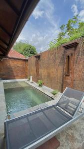 a swimming pool in front of a brick wall at chrome hotel & resort solo in Tjolomadu