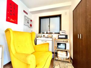 un soggiorno con una sedia gialla e un microonde di 難波無印ノ家 ad Osaka