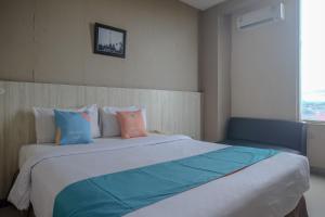 a bedroom with a large bed with pillows and a window at Sans Hotel Lynt Makassar in Makassar