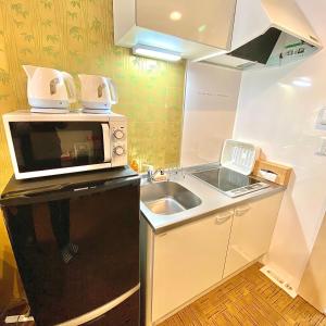 une petite cuisine avec un micro-ondes et un évier dans l'établissement Guest House One More Heart at Kyoto Station South 5, à Kyoto