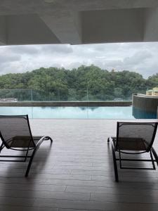 two chairs sitting on a building with a swimming pool at Golden Oceanview at Icon Residence in Kuala Terengganu