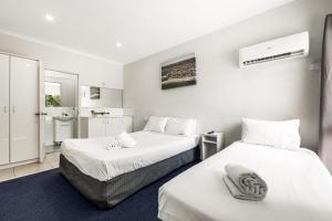 two beds in a room with white walls at Central Motel Mooloolaba and Apartments in Mooloolaba