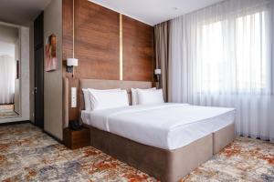un grande letto in una stanza con una grande finestra di Grand Mildom Hotel a Almaty