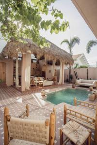 a swimming pool with two chairs and a thatch roof at Gorgeous luxury 1 bedroom villa in heart of Canggu in Canggu