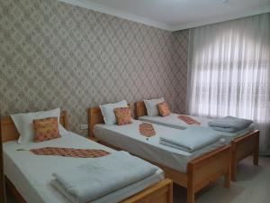 a bedroom with two beds and a window at Qamar Hotel in Bukhara