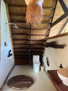baño con aseo y techo de madera. en The Beach House Ocam Ocam en Busuanga