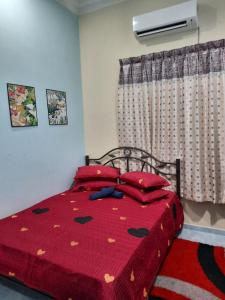 1 dormitorio con 1 cama con edredón rojo y ventana en MUAZDIANA HOMESTAY di KUALA NERUS, GONG BADAK, en Kampong Tanjong Gelam