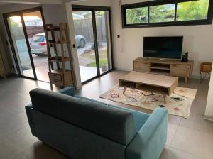 ein Wohnzimmer mit einem blauen Sofa und einem TV in der Unterkunft Villa avec piscine au centre de la rivière in Saint-Louis