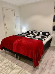 a bedroom with a bed with a red blanket on it at Guest House Koskenkylä in Rovaniemi