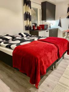 a bedroom with a bed with a red blanket on it at Guest House Koskenkylä in Rovaniemi