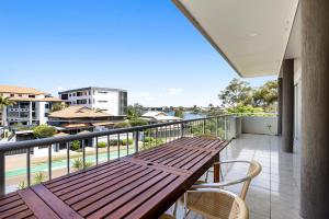 eine Terrasse mit einem Holztisch und Stühlen auf dem Balkon in der Unterkunft Central Motel Mooloolaba and Apartments in Mooloolaba