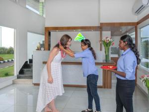 Uma mulher de vestido está a ajudar uma mulher na cozinha. em Sprise Munnar Resort and Spa em Munnar