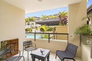 balcone con sedie, tavolo e piscina di 119 Santai Resort - Poolside Apartment by uHoliday a Casuarina