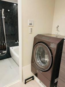 uma máquina de lavar roupa na casa de banho ao lado de uma banheira em 1204 ブランシエラ那覇曙プレミスト em Nakanishi
