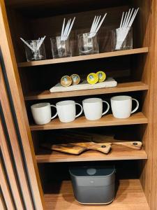 un estante con tazas y utensilios en un armario en 1204 ブランシエラ那覇曙プレミスト, en Nakanishi