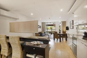 a kitchen and living room with a table and chairs at 119 Santai Resort - Poolside Apartment by uHoliday in Casuarina