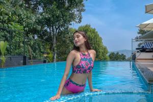 a woman in a bikini sitting on the edge of a swimming pool at Sprise Munnar Resort and Spa in Munnar