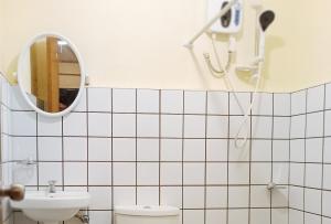 La salle de bains est pourvue de carrelage blanc, d'un lavabo et d'un miroir. dans l'établissement Maribel’s Pension Sindangan, à Sindangan