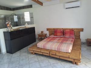1 Schlafzimmer mit einem Holzbett und einem Badezimmer in der Unterkunft Appartement à la campagne avec spa 3 nuits minimum in Le Lamentin