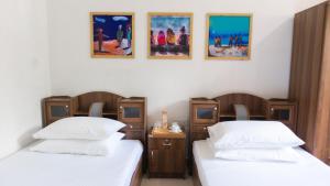 2 Betten in einem Zimmer mit Gemälden an der Wand in der Unterkunft Palm Rest Maldives in Magoodhoo