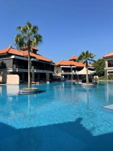 une grande piscine avec des palmiers en face d'un bâtiment dans l'établissement Luxury 1BR apartment in Anantara Hotel Palm Jumeirah connected Anantara Hotel, à Dubaï