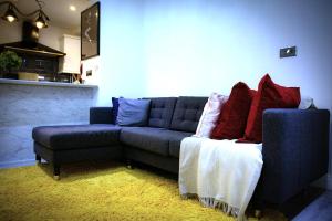 uma sala de estar com um sofá azul e almofadas vermelhas em Rostron House em Manchester