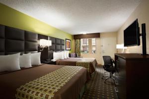 a hotel room with two beds and a flat screen tv at Days Inn by Wyndham Dallas Irving in Irving