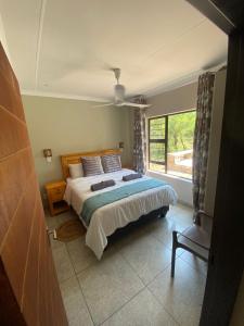 a bedroom with a bed and a large window at Sonador Bush House in Marloth Park