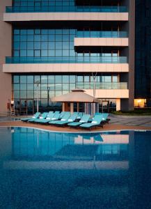 a pool with lounge chairs in front of a building at Millennium Place Barsha Heights Hotel in Dubai