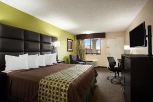 a hotel room with a bed and a television at Days Inn by Wyndham Dallas Irving in Irving