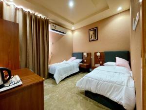 una camera d'albergo con 2 letti e una scrivania di Dahreez motel a Qurţah