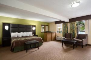 a hotel room with a bed and a chair at Days Inn by Wyndham Dallas Irving in Irving
