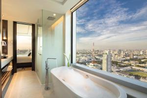 a bath tub in a bathroom with a view of a city at Eastin Grand Hotel Phayathai in Bangkok