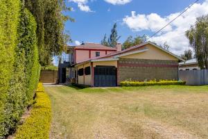 a house with a hedge in front of a yard at Kenai Stay, Secluded 1 bedroom with free parking in Nanyuki