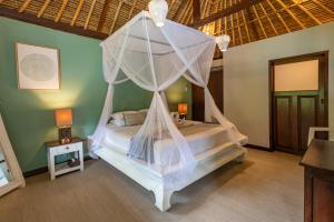 a bedroom with a bed with a mosquito net at Villa Coco Bali in Seminyak