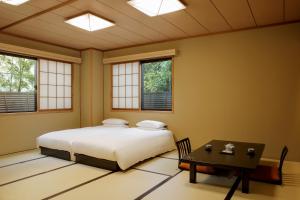 a bedroom with a bed and a table and windows at Gion Ryokan Karaku in Kyoto