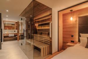 a bedroom with a glass wall and a bed at Wirthshof Hotel & Chalets in Markdorf