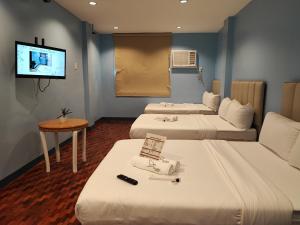 Habitación de hotel con 3 camas y TV de pantalla plana. en Glory Hotel Cubao en Manila