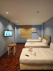 a room with three beds and a flat screen tv at Glory Hotel Cubao in Manila