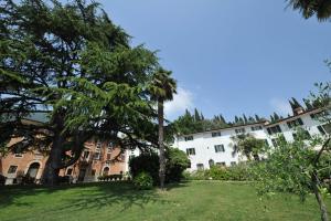 een groot wit gebouw met bomen in een tuin bij La Corte dei Limoni in Caprino Veronese