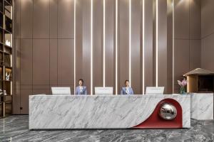 two people sitting at a reception desk in a lobby at Jinshi Hotel in Guangzhou