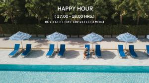 a woman sitting on a beach with chairs and umbrellas at Seabed Grand Hotel Phuket - SHA Extra Plus in Phuket Town