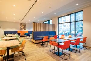 un restaurant avec des tables, des chaises et des fenêtres dans l'établissement LOGINN Hotel Berlin Airport, à Berlin