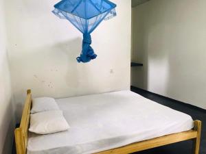 een bed in een kamer met een blauwe lamp aan de muur bij Nature Inn in Mirissa